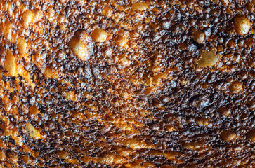 Close-up of burnt toast with a detailed textured surface and dark colors