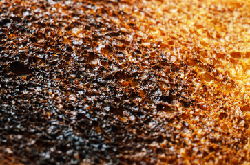 Close-up of burnt toast texture showing charred surface and golden-brown areas