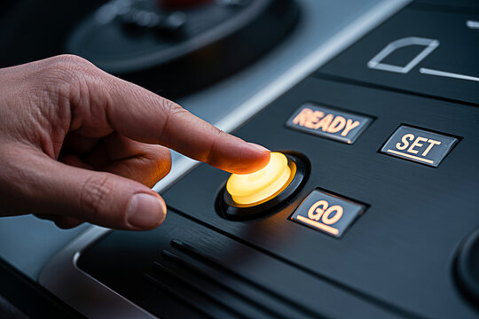Finger presses a glowing yellow 'Go' button on a modern control panel with 'Ready' and 'Set' options suggesting activation initiation or starting a process in technology or machinery