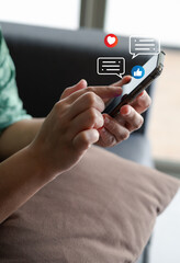 Close-up of a person using smartphone with social media icons, like, heart, and chat notification, representing online communication, social interaction, and digital connection in modern lifestyle.