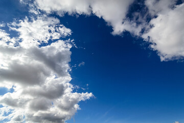 Cielo azul profundo y brillante con nubes cúmulo blancas y estelas de condensación en un día soleado
