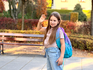 Young girl waving goodbye in autumn park
