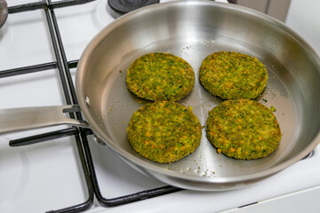 Four vegan burger patties frying in a stainless steel pan, natural plant-based food concept