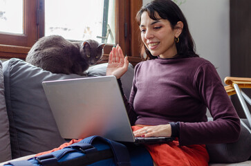 Young disabled woman having a video call on laptop with her cat.