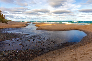 River flow through sand beach to lake shore