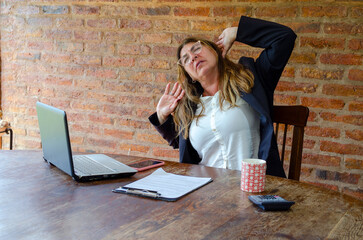 Mature woman worker suffering of pain on neck and back.Woman employee stretching in pain.
