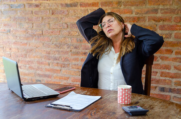 Mature woman worker suffering of pain on neck and back.Woman employee stretching in pain.