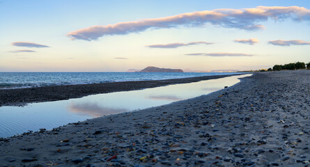 Tranquil Pebble Beach with Reflections at Sunset in Crete