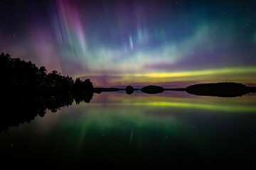 Northern lights dancing over clam lake in Farnebofjarden national park in north of Sweden.