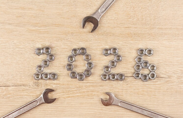 Light wood background with number 2026 by metal nuts with wrenches. 2026 year