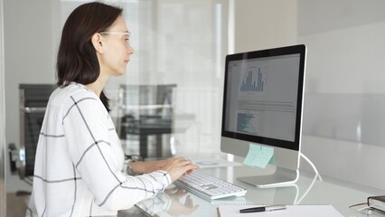Woman analyst working on computer, analyzing business data with charts and graphs, marketing report on screen. Businesspeople concept