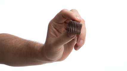 Hand holding a small chocolate treat against a plain white background