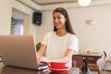 Young Asian woman working on laptop at cafe during daytime
