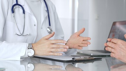 Doctor discussing medical information with patient during consultation, showing healthcare advice and diagnostic data on laptop. Medicine, healthcare and science concept