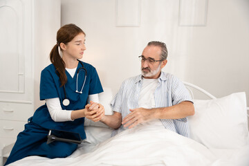 Obraz premium Home care nurse giving medication and water to elderly man in bedroom. Professional caregiver assisting senior patient with daily medical needs in a comfortable and supportive home environment.