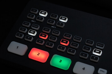 Professional video switcher and software control panel in audiovisual production setup with glowing buttons and screens.