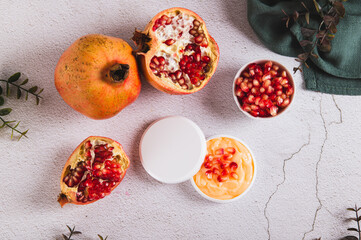 Pomegranate skin care cream in a jar and fruit on the table top view