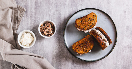 Ricotta and tuna salad on a grain bread burger on a plate on a table top view web baanner