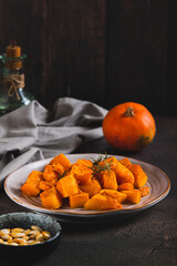 Pieces of baked pumpkin with rosemary on a plate on the table vertical view