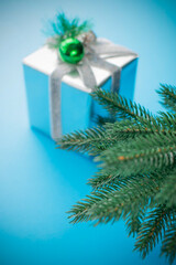 Festive Silver Gift Box with Pine Branch on Vibrant Blue Background
