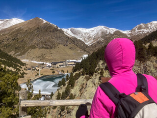Fototapeta premium Hiker viewing Vall de Nuria sanctuary and frozen lake