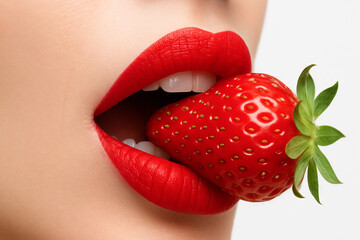 Close-up of red lips biting a strawberry showcasing bold color and sensuality. concept of temptation, fresh fruit, beauty