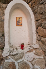 Small roadside shrine with candles and potted plants against rocky wall