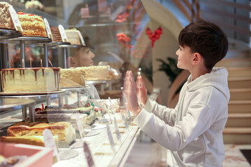 Child craving sweets in a bakery display, symbolizing sugar addiction, unhealthy diet, and awareness of childhood nutrition and diabetes prevention