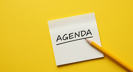 Agenda written on a sticky note with a pencil on yellow background
