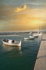 Traditional fishing boats and yachts docked at a peaceful harbor during golden sunset