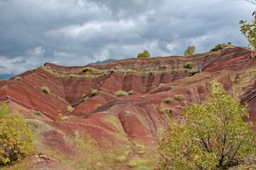 Layered rock formations of the Zagros Mountains, featuring distinctive red and green sedimentary strata under a clear sky in Kurdistan