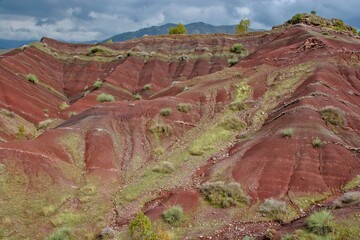 Layered rock formations of the Zagros Mountains, featuring distinctive red and green sedimentary strata under a clear sky in Kurdistan