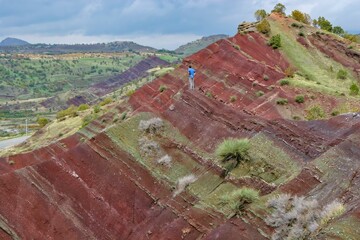 Layered rock formations of the Zagros Mountains, featuring distinctive red and green sedimentary strata under a clear sky in Kurdistan