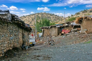 Traditional rural life in a Kurdish village, featuring a weathered stone and wood shelter and a dirt path