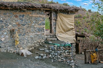 Traditional rural life in a Kurdish village, featuring a weathered stone and wood shelter and a dirt path