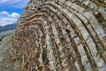 Layered rock formations of the Zagros Mountains, featuring distinctive red and green sedimentary strata under a clear sky in Kurdistan