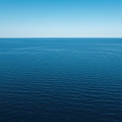 Obraz premium Expansive deep blue ocean water stretching toward the distant horizon on a clear, sunny day. The vast open sea provides a tranquil background for nature themes, blue, tranquil, deep