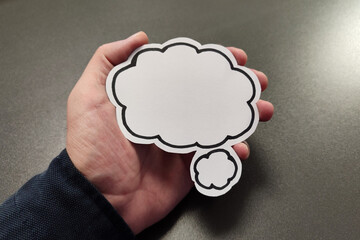 Hand holding blank white speech bubble on black background