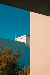 Lightning rod on top of minimalist modern building under clear blue sky, illuminated by sunset light with autumn willow tree beside facade, safety and architecture concept.