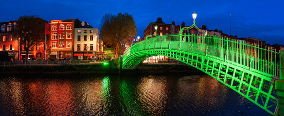 Ha'penny Bridge or Droichead na Life, refurbished 19th-century cast-iron span illuminated in green at night over River Liffey, Dublin, Ireland.