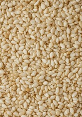 Fototapeta premium White sesame seeds scattered on a plain background, viewed up close, showing texture and detail, ready for cooking or baking use ,white ,plant based ,food