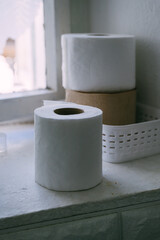 Roll of toilet paper placed on window sill in old rustic bathroom.