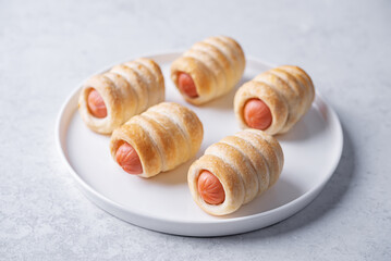 Sausage in dough, hot dog bread mini in a plate on a white background