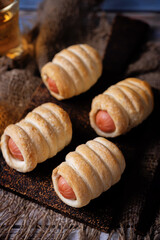 Sausage in dough, hot dog bread mini in a plate on a wood background