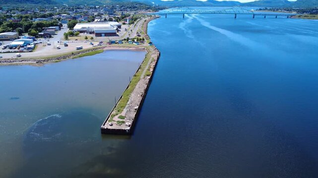 Aerial view of the remains of an old abandoned wharf along the Restigouche River with a cantilever bridge in the background. Campbellton,NB,Canada,2025.