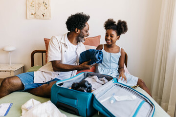 Happy father and daughter packing for a family vacation together