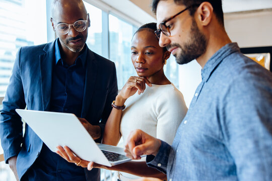 Group analyzing laptop work in an office setting - Powered by Adobe