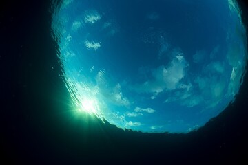 Underwater photo, where you can see some clouds and Sun