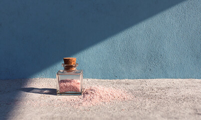 Himalayan pink salt in glass bottle with cork stopper on textured background