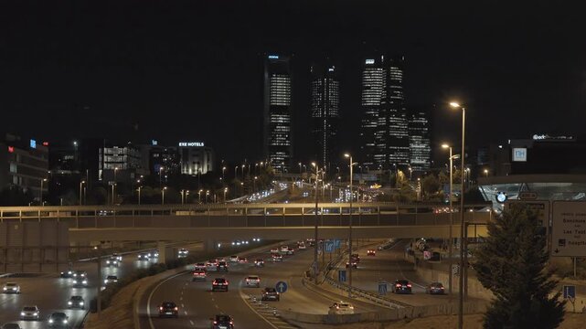 Evening view of Madrid&rsquo;s M30 highway with car lights and the Cuatro Torres Business Area illuminated in the background